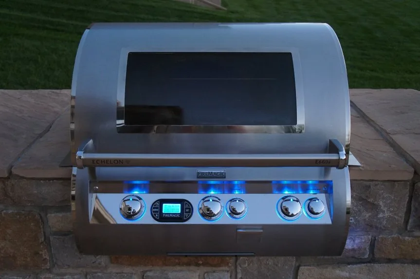 A Fire Magic grill with the hood open on a stone outdoor kitchen island in Kansas City